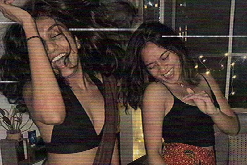 Two friends dancing and laughing at a house party, shot on Home Video with tape lines and soft color