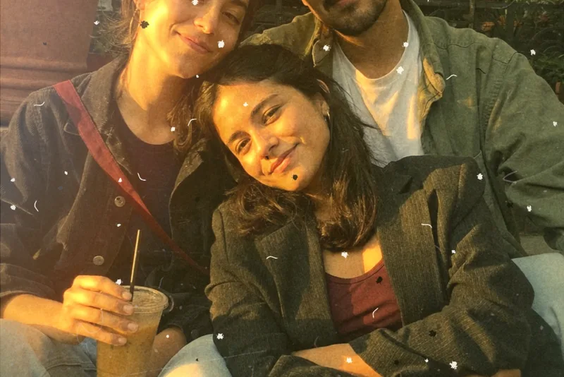 Three friends leaning on each other at golden hour, shot on Gold Snap with a warm light leak